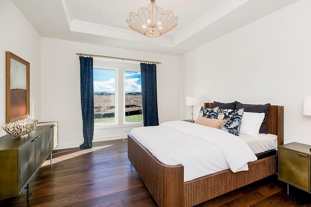 bedroom featuring crown molding, an inviting chandelier, dark hardwood / wood-style floors, and a raised ceiling