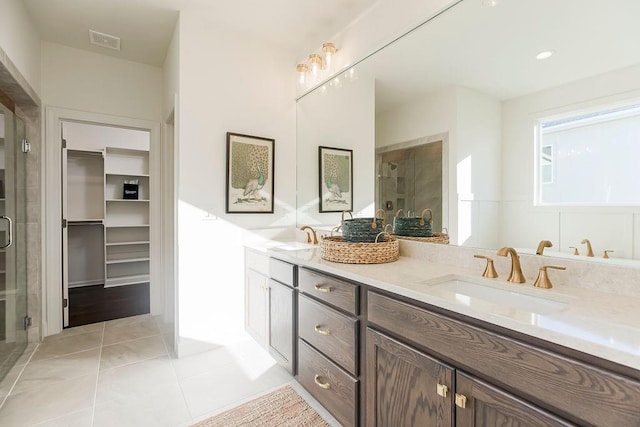 bathroom with a shower with door, tile patterned floors, and vanity