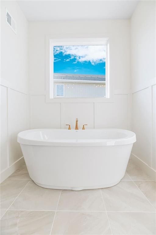 bathroom with tile patterned flooring, a bathtub, and a wealth of natural light