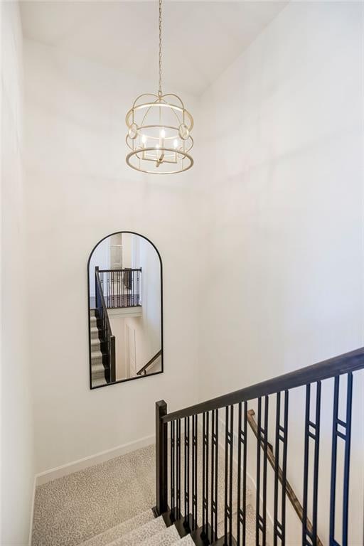 stairs with carpet floors and an inviting chandelier