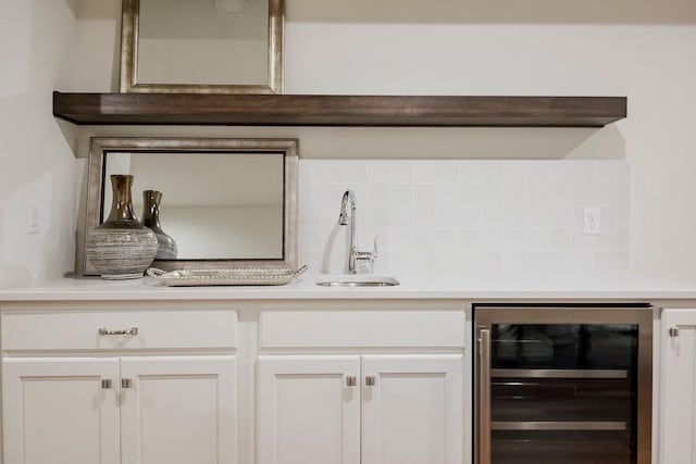 bar featuring beverage cooler, sink, and white cabinetry