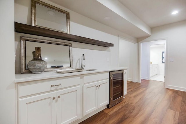 kitchen featuring beverage cooler, dark hardwood / wood-style floors, sink, and white cabinetry