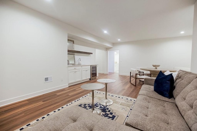 living room with beverage cooler, sink, and light wood-type flooring