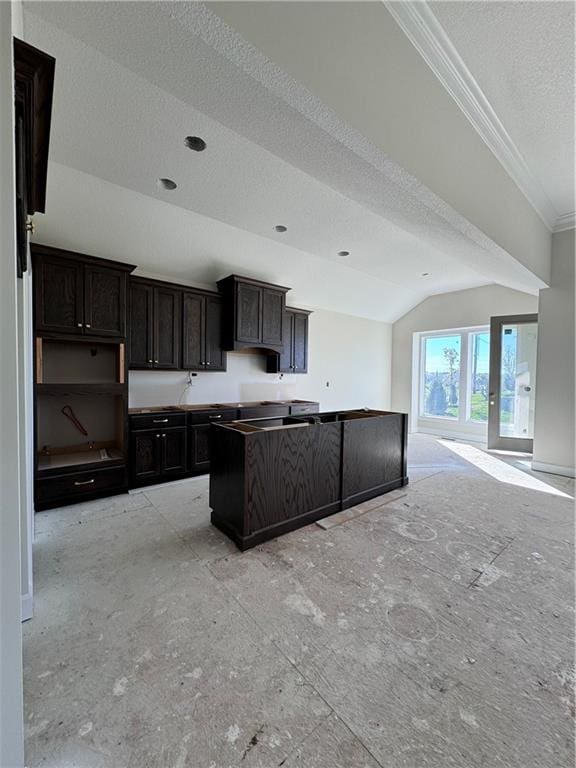 kitchen featuring lofted ceiling, a center island, crown molding, dark brown cabinets, and a textured ceiling