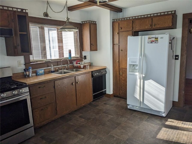 kitchen featuring stainless steel gas range oven, decorative light fixtures, white fridge with ice dispenser, dishwasher, and sink