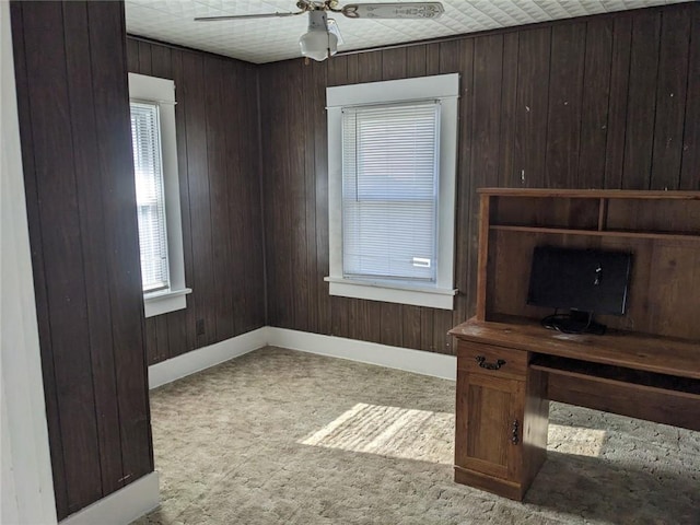 living room featuring ceiling fan, light carpet, and wood walls