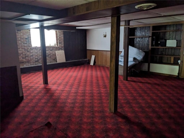 basement featuring brick wall and dark colored carpet