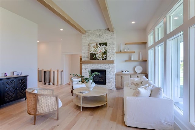 living room with beamed ceiling, light hardwood / wood-style flooring, a wealth of natural light, and a fireplace