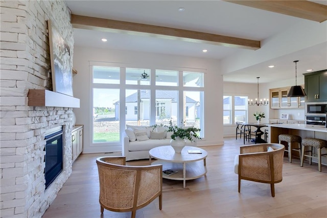 living room featuring a fireplace, beam ceiling, light hardwood / wood-style floors, and a notable chandelier