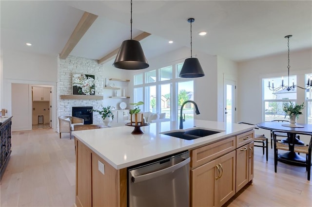 kitchen with a fireplace, stainless steel dishwasher, plenty of natural light, and an island with sink