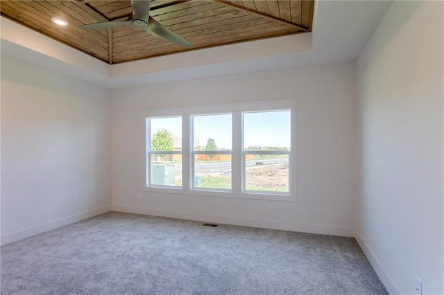 carpeted empty room featuring ceiling fan, wood ceiling, and a tray ceiling