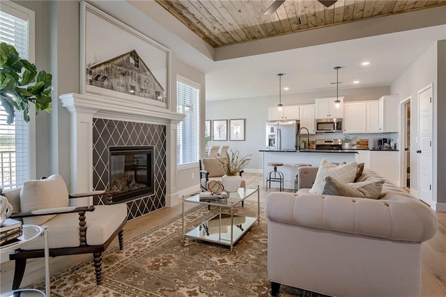 living room featuring wooden ceiling, a healthy amount of sunlight, a fireplace, and wood-type flooring