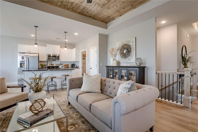 living room featuring light hardwood / wood-style flooring, sink, and wooden ceiling