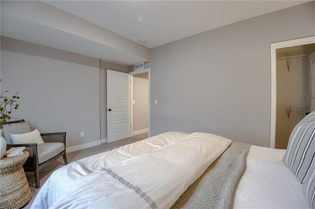 bedroom with light carpet, a closet, and a walk in closet