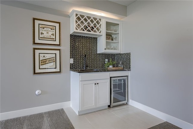 bar with decorative backsplash, light tile patterned flooring, white cabinets, beverage cooler, and sink