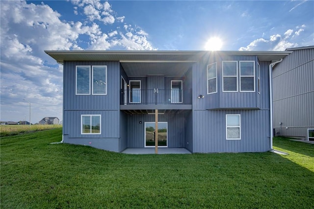 rear view of property with a balcony and a yard