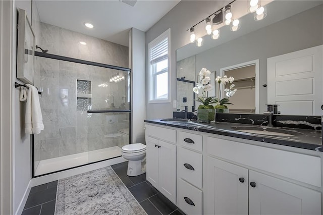 bathroom with walk in shower, vanity, tile patterned flooring, and toilet