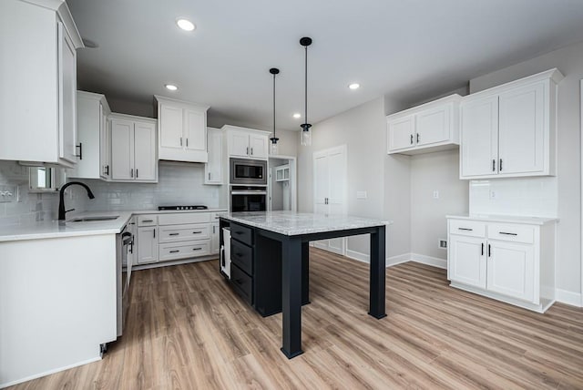 kitchen featuring stainless steel appliances, a kitchen island, a kitchen breakfast bar, tasteful backsplash, and light hardwood / wood-style flooring