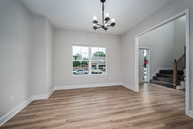 empty room with light hardwood / wood-style flooring and an inviting chandelier