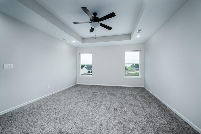 carpeted empty room featuring ceiling fan and a tray ceiling