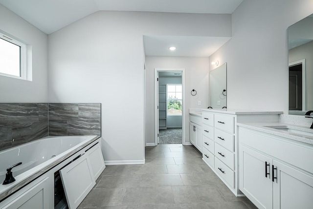 bathroom with lofted ceiling, a washtub, tile floors, and vanity