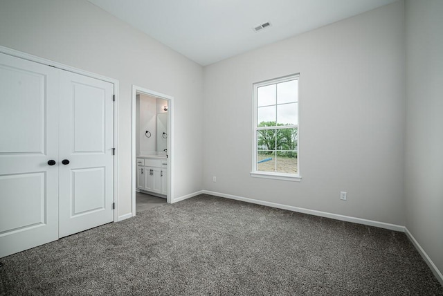 unfurnished bedroom with a closet, connected bathroom, and carpet floors