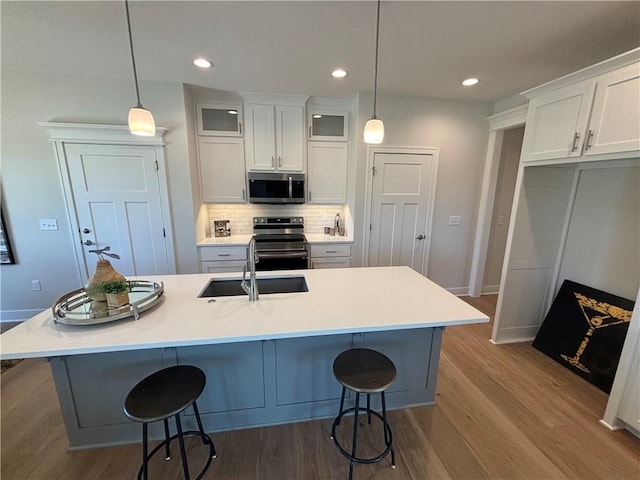 kitchen with white cabinets, pendant lighting, stainless steel appliances, and light wood-type flooring