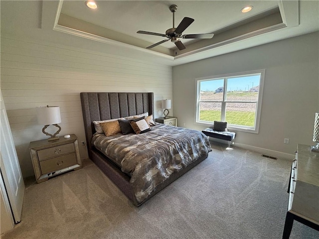 carpeted bedroom featuring ceiling fan and a tray ceiling