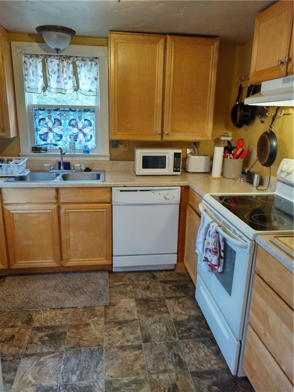 kitchen featuring white appliances, dark tile flooring, and sink