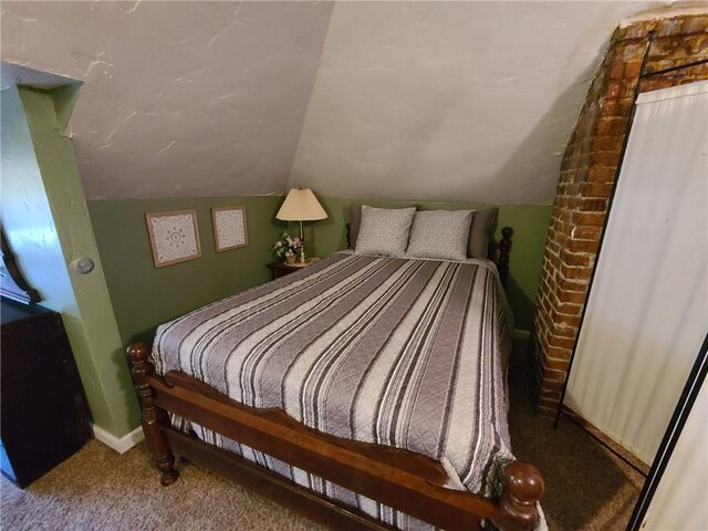 bedroom with brick wall, carpet, and vaulted ceiling