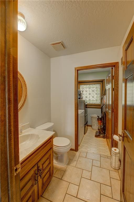 bathroom with toilet, tile flooring, a textured ceiling, washer and dryer, and large vanity