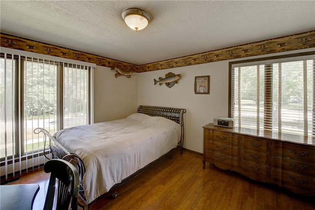 bedroom with a textured ceiling and dark hardwood / wood-style floors