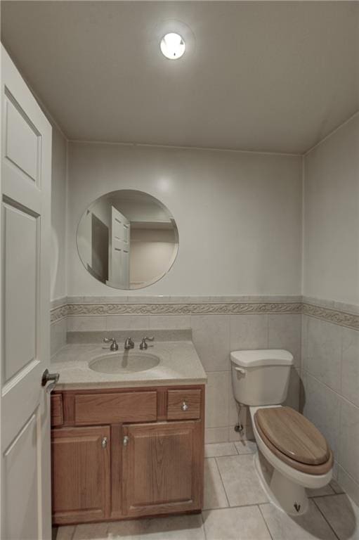 bathroom featuring vanity, tile floors, toilet, and tile walls