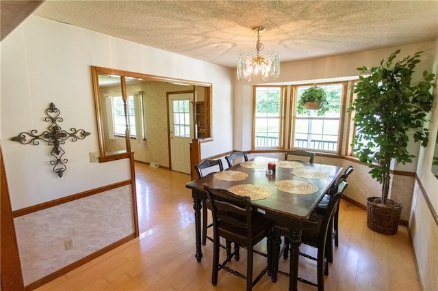 dining space featuring a notable chandelier, a textured ceiling, and light hardwood / wood-style flooring