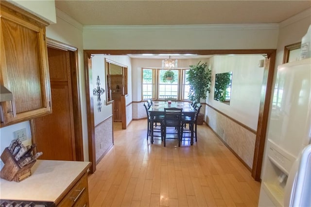 dining space featuring an inviting chandelier, ornamental molding, and light wood-type flooring