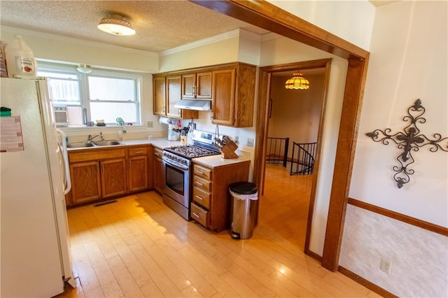 kitchen featuring sink, white refrigerator, light hardwood / wood-style flooring, gas range, and a textured ceiling