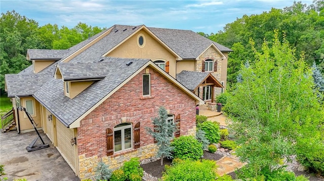 29800 E 65th St, Blue Springs, MO 64014 - view of front facade featuring stucco siding, roof with shingles, stone siding, and a patio area