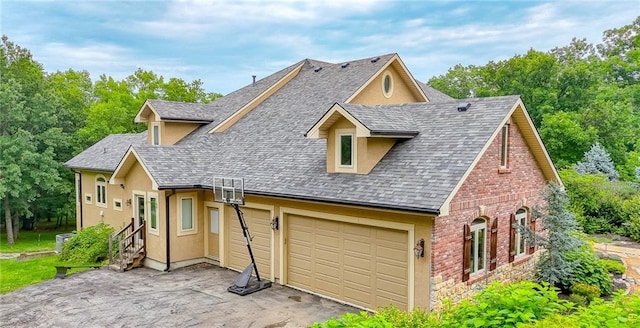 29800 E 65th St, Blue Springs, MO 64014 - view of front facade with a shingled roof, stucco siding, driveway, brick siding, and view of wooded area