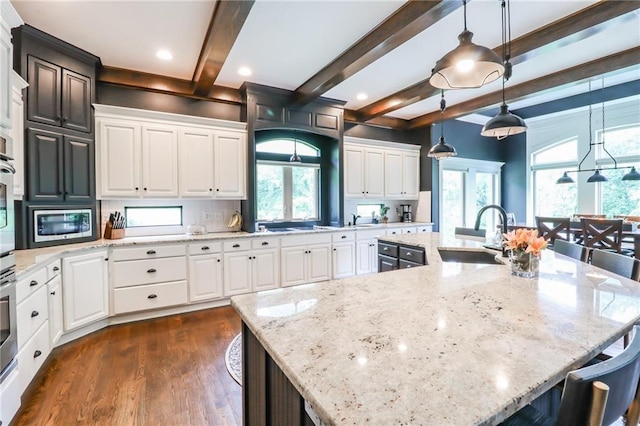 29800 E 65th St, Blue Springs, MO 64014 - kitchen with a sink, a breakfast bar area, stainless steel microwave, dark wood finished floors, and beam ceiling