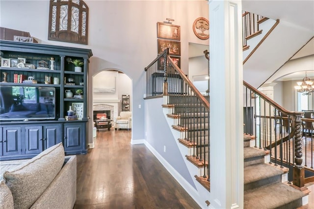 29800 E 65th St, Blue Springs, MO 64014 - stairs with arched walkways, wood finished floors, a fireplace, a chandelier, and baseboards