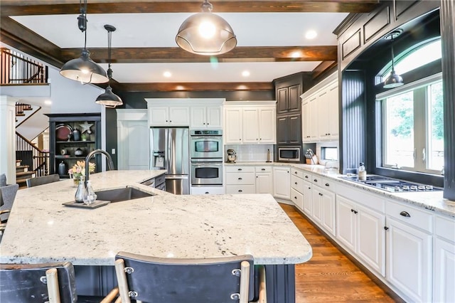 29800 E 65th St, Blue Springs, MO 64014 - kitchen featuring a sink, stainless steel appliances, beamed ceiling, a large island with sink, and wood finished floors
