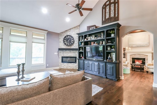 29800 E 65th St, Blue Springs, MO 64014 - living room featuring a stone fireplace, a ceiling fan, high vaulted ceiling, dark wood finished floors, and arched walkways
