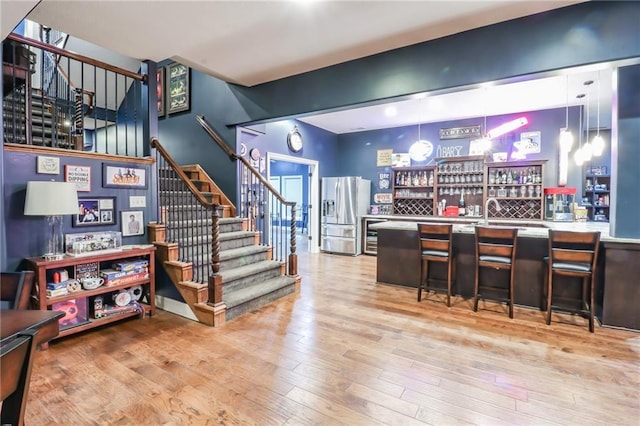 29800 E 65th St, Blue Springs, MO 64014 - indoor bar with stainless steel refrigerator with ice dispenser, stairs, wood-type flooring, and pendant lighting