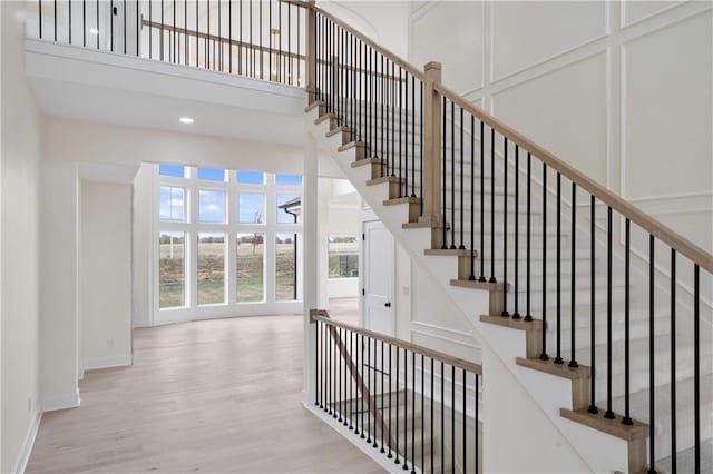 staircase with a towering ceiling and hardwood / wood-style flooring