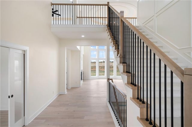 stairway featuring french doors, hardwood / wood-style flooring, and a high ceiling