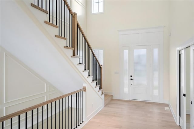 entrance foyer with a towering ceiling and light hardwood / wood-style flooring