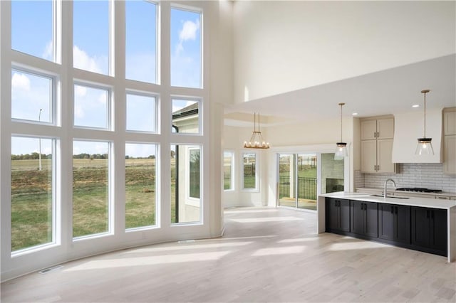 kitchen featuring light wood-type flooring, a towering ceiling, and plenty of natural light