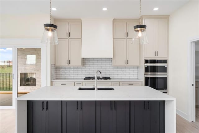 kitchen with a spacious island, light stone counters, appliances with stainless steel finishes, and hanging light fixtures