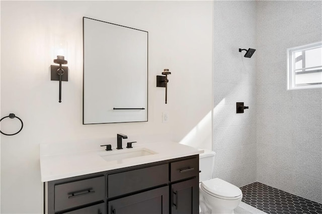 bathroom featuring toilet, vanity, and tiled shower