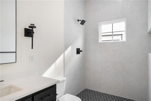 bathroom with vanity, a tile shower, and toilet